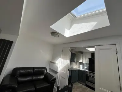 a living room with a black leather couch and a skylight at Seagull studio in Felixstowe