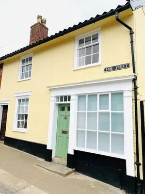 a yellow and white building with a green door at The Yellow cottage on the hill. in Framlingham