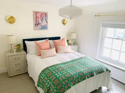 a bedroom with a bed with pink pillows and a window at The Yellow cottage on the hill. in Framlingham