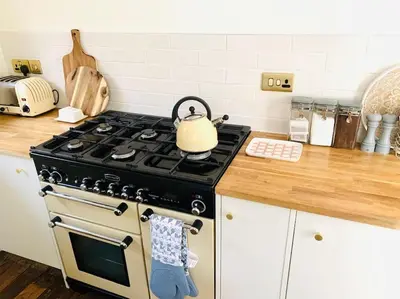 a kitchen with a stove with a tea kettle on it at The Yellow cottage on the hill. in Framlingham