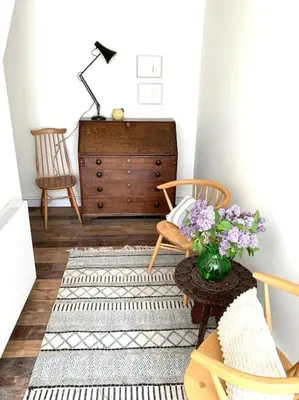 a living room with a chair and a dresser with flowers at The Yellow cottage on the hill. in Framlingham