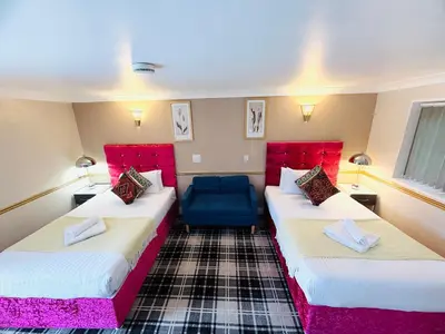 a room with two beds and a blue couch at 4 Sisters Inn in Theydon Bois