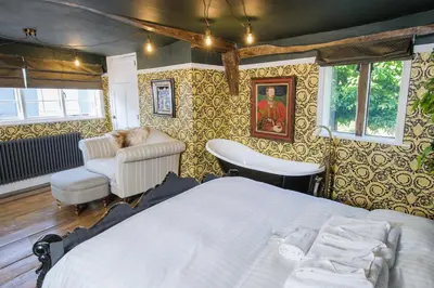 a bedroom with a bed and a chair at Luxury 8 Bed Manor House Hot Tub Cinema Room SkyTV in Saffron Walden