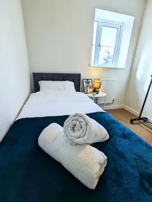 a bed with two towels sitting on top of it at 3-Bed, Sleeps 5, 3 Bath, Parking, WiFi in Watton