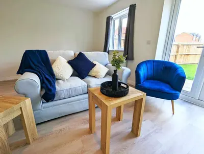 a living room with a couch and a blue chair at 3-Bed, Sleeps 5, 3 Bath, Parking, WiFi in Watton