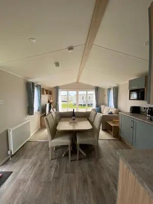 a kitchen and living room with a table and chairs at VerbZen Holiday Caravan at St Osyth Beach, Clacton-on-Sea by Verb Holidays in Saint Osyth