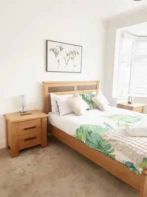 a bedroom with a bed with a wooden frame and a table at Spacious 3 Bedroom Home, Sleeps 7, Long-Stay & Contractor Friendly, Family & Professional Ready, Clark Property Estates in Southend-on-Sea