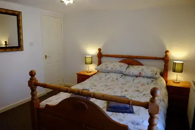 a bedroom with a wooden bed with two lamps at Cosy Cottage to Relax or Explore in Mistley