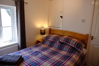 a bedroom with a bed with a plaid blanket and a window at Cosy Cottage to Relax or Explore in Mistley