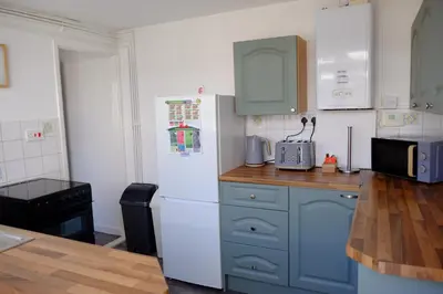 a kitchen with blue cabinets and a white refrigerator at Cosy Cottage to Relax or Explore in Mistley