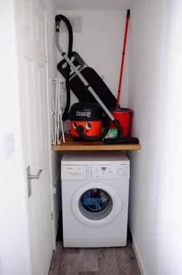 a laundry room with a washing machine and tools on a shelf at Cosy Cottage to Relax or Explore in Mistley