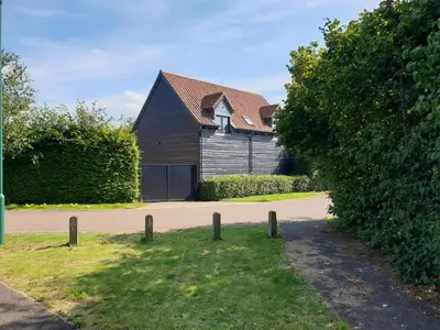 a large wooden building with a gate in front of a house at Bluebell Lodge in Longstowe