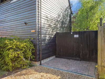 a wooden fence next to a house with a gate at Bluebell Lodge in Longstowe