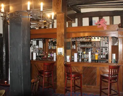 a bar in a restaurant with wooden walls and chairs at Brook Red Lion Hotel in Colchester