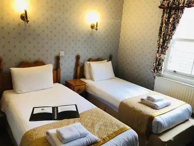 a hotel room with two beds and a window at Brook Red Lion Hotel in Colchester