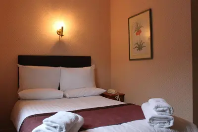 a hotel room with a bed with towels on it at Brook Red Lion Hotel in Colchester