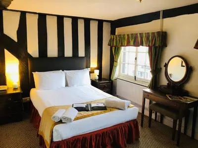 a hotel room with a bed and a mirror at Brook Red Lion Hotel in Colchester