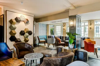 a lobby with leather chairs and tables at The George Hotel Colchester in Colchester