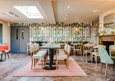 a restaurant with tables and chairs and a fireplace at The George Hotel Colchester in Colchester