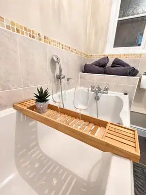 a bathroom with a bath tub with two wine glasses on it at 2-Bed, Sleeps 5, 2 Bath, Parking, WiFi in Colchester