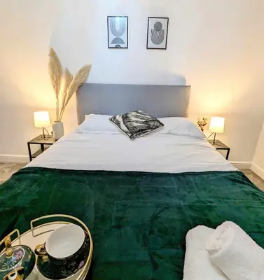 a bedroom with a large green bed with two lamps at 2-Bed, Sleeps 5, 2 Bath, Parking, WiFi in Colchester