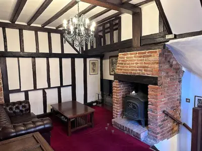 a living room with a brick fireplace and a chandelier at Characterful house in Hertford - near London in Hertford