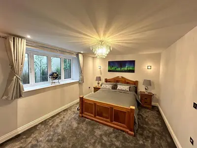 a bedroom with a bed and a window and a chandelier at Stansted Airport Stay, Parking and Luxury Suite in Bishops Stortford