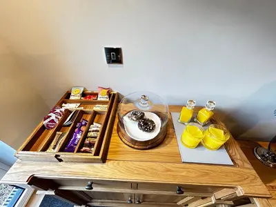 a wooden table with a cake and drinks on it at Stansted Airport Stay, Parking and Luxury Suite in Bishops Stortford