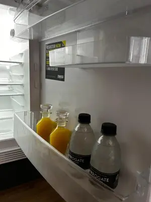 three bottles of orange juice in an open refrigerator at Stansted Airport Stay, Parking and Luxury Suite in Bishops Stortford