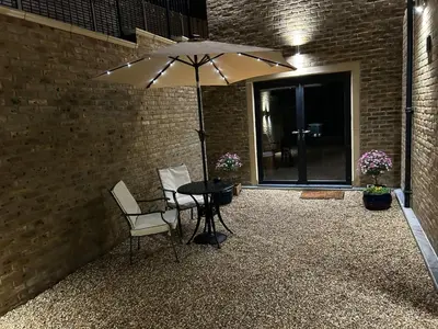 a patio with a table and two chairs and an umbrella at Stansted Airport Stay, Parking and Luxury Suite in Bishops Stortford