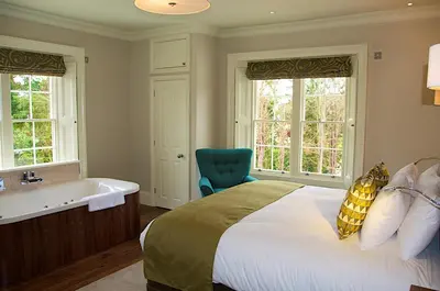 a bedroom with a bed and a bathtub and a bed and a chair at The Oaksmere in Eye