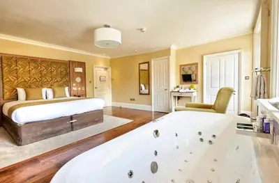 a bedroom with a large bed and a bath tub at The Oaksmere in Eye
