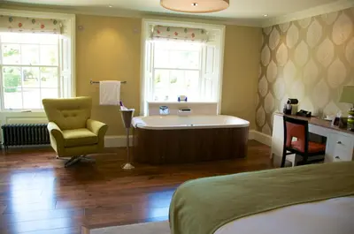 a bathroom with a tub and a chair and a bed at The Oaksmere in Eye