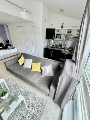 a grey couch with yellow pillows in a living room at Studio - Sleeps 3 - Parking - Wifi in Cambridge