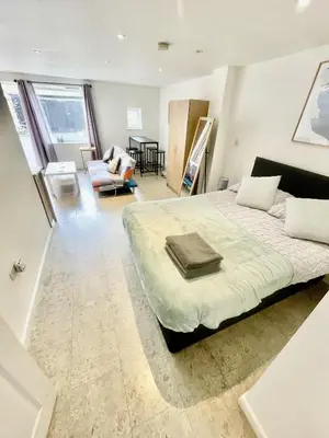 a bedroom with a large bed and a living room at Studio - Sleeps 2 - Parking - Wifi in Cambridge