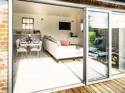 a living room with sliding glass doors leading into a living room at The Workshop by The Suffolk Cottage Collection in Bruisyard