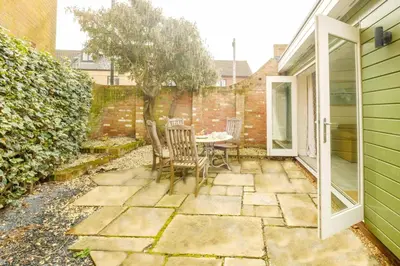 a patio with a table and chairs and a tree at Tanyard House in Woodbridge