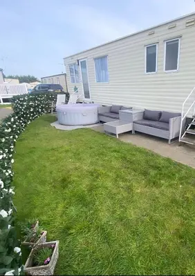 a patio with couches and a lawn in front of a house at Coastal caravan retreat in Brightlingsea