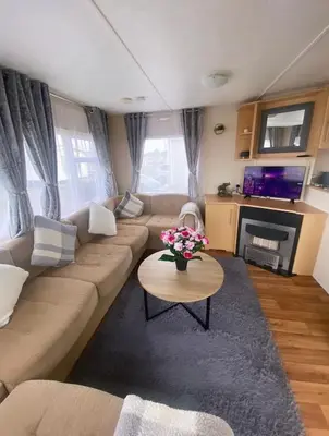 a living room with a couch and a table with flowers at Coastal caravan retreat in Brightlingsea