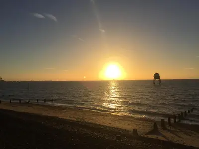 a sunset on the beach with a pier in the water at AcLand Lodge Dovercourt West in Harwich