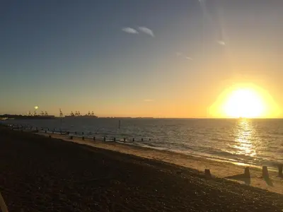 a beach with the sun setting over the water at AcLand Lodge Dovercourt West in Harwich