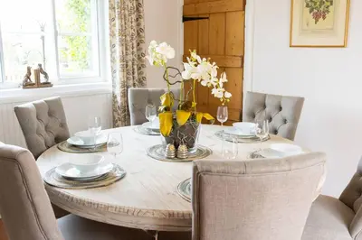 a dining room table with chairs and a wooden table with flowers at Charming 4 Bed Cottage in Herts Countryside - Pass the Keys in Sacomb