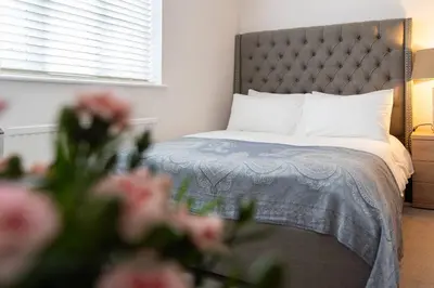 a bedroom with a bed with pink flowers in the foreground at Charming 4 Bed Cottage in Herts Countryside - Pass the Keys in Sacomb