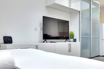 a white bedroom with a tv and a bed at Pass the Keys Central Modern Cabin on Mill Road in Cambridge