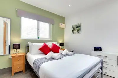 a bedroom with a large white bed with red pillows at Pass the Keys Central Modern Cabin on Mill Road in Cambridge