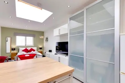 a kitchen with a large glass partition with a living room at Pass the Keys Central Modern Cabin on Mill Road in Cambridge