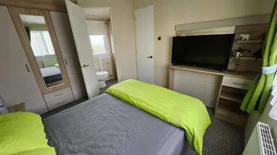 a small room with a bed and a flat screen tv at Pura Vida Caravan in Saint Osyth