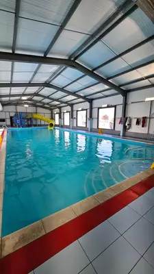 a large indoor swimming pool with blue water at Pura Vida Caravan in Saint Osyth