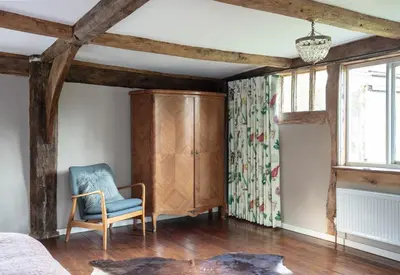 a bedroom with a blue chair and a dresser at Brook Farm in Harleston