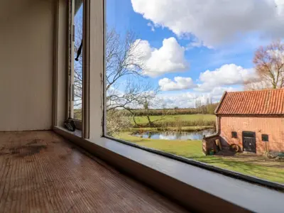 an empty room with a window looking out at a barn at Brook Farm in Harleston